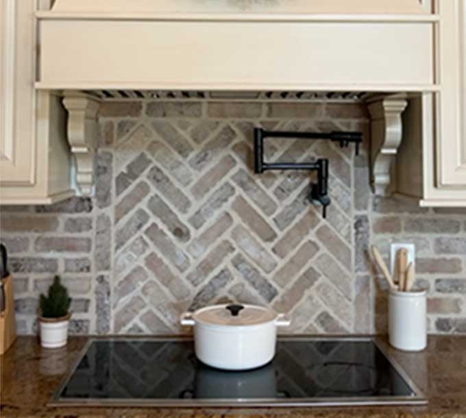 thin brick backsplash over stovetop with a cooking pot on it