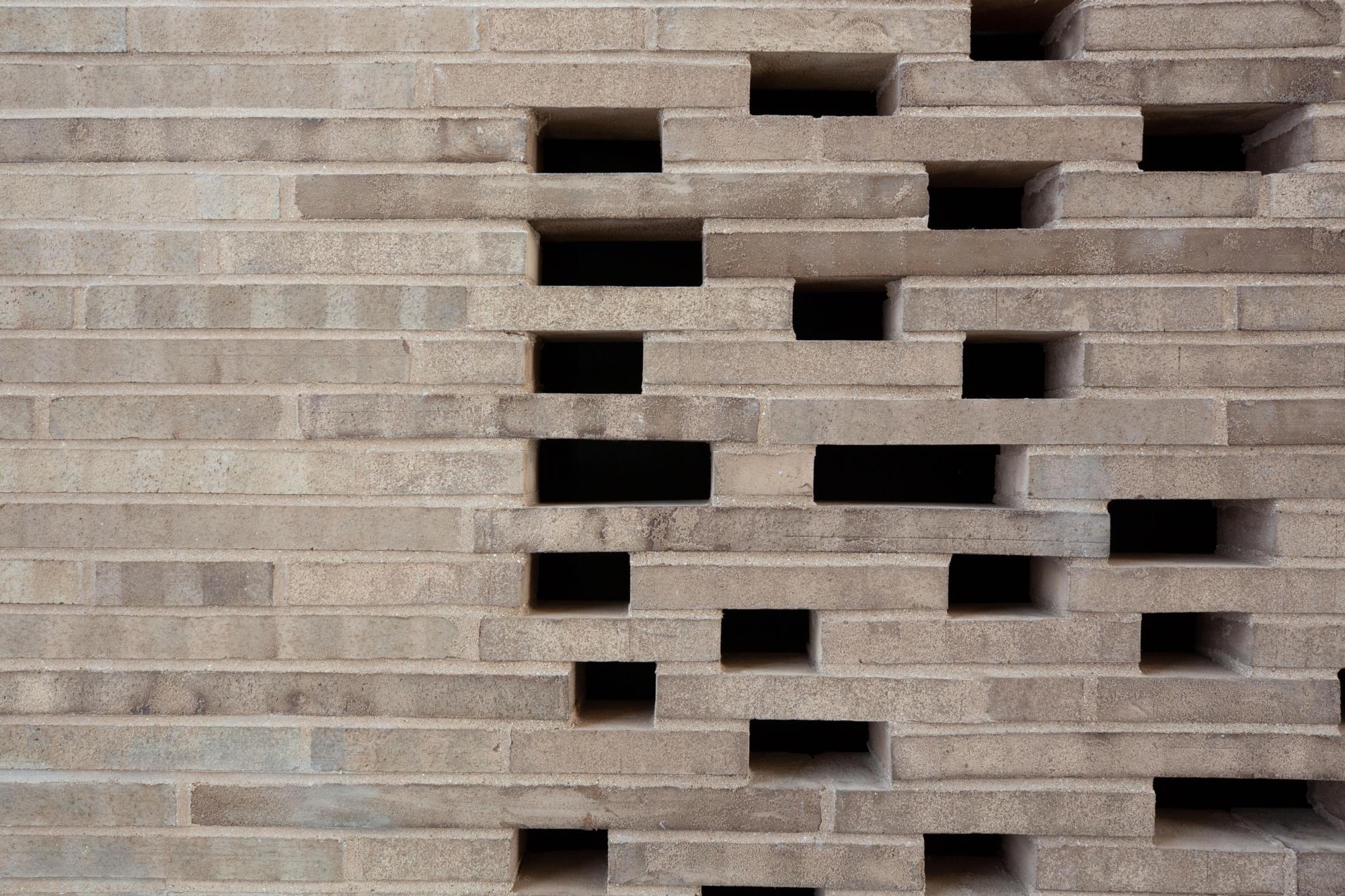 Image of the textured, lightly colored brick of the outer wall of the 175 West 10th Street House